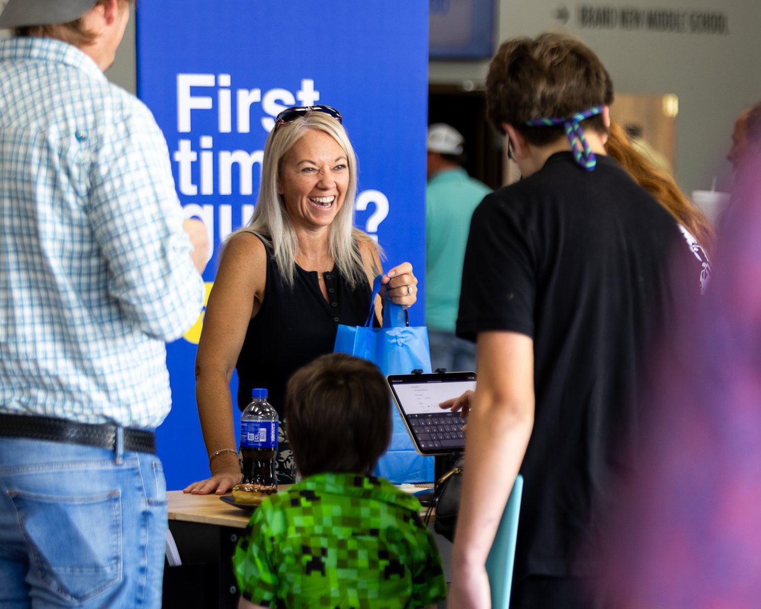 A greeter welcoming guests at the First Time Guest table